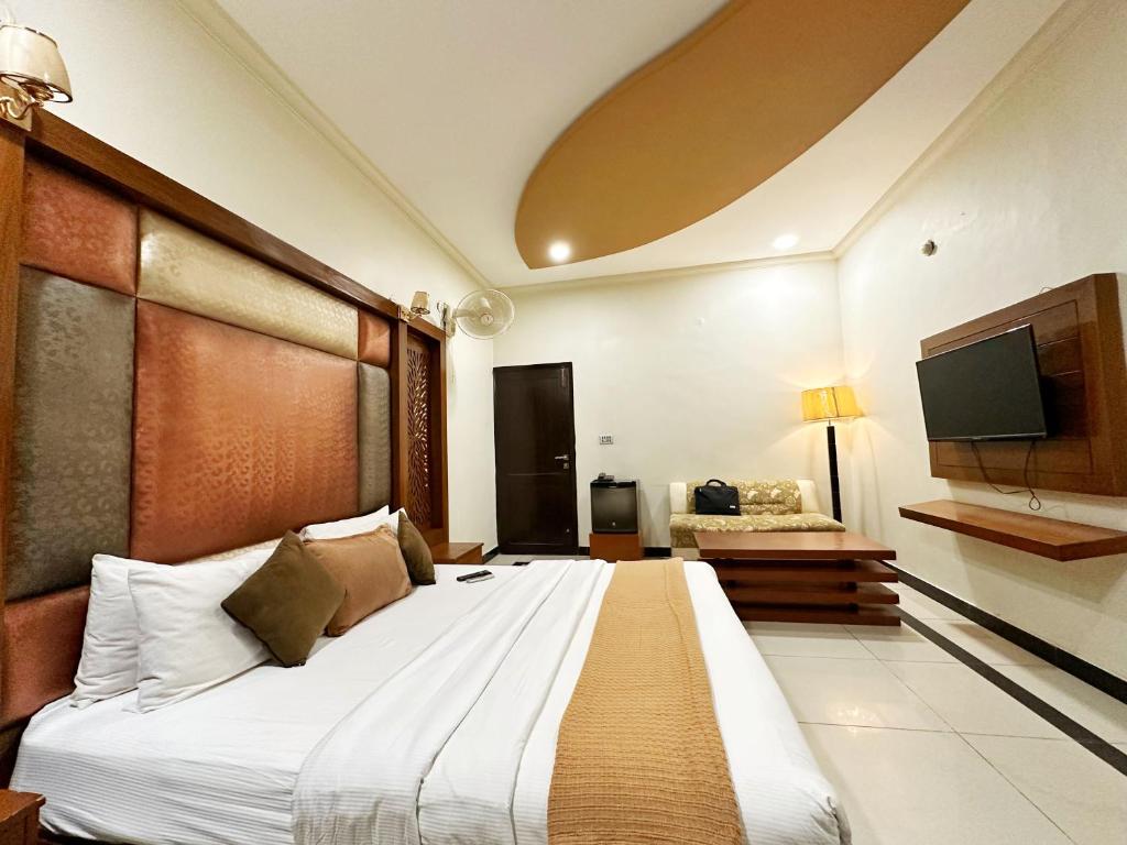 a bedroom with a large bed and a television at The Grand Hotel Multan in Multan