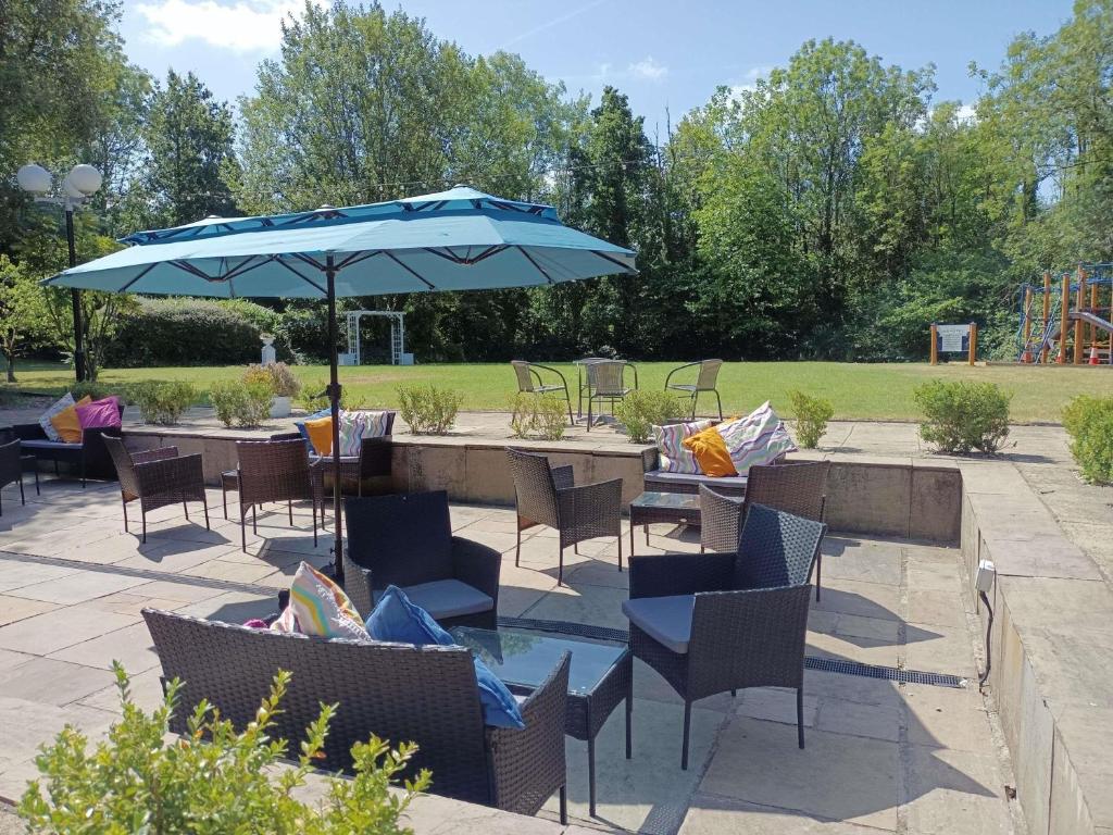 a patio with a table and chairs and an umbrella at Novotel Manchester West in Worsley