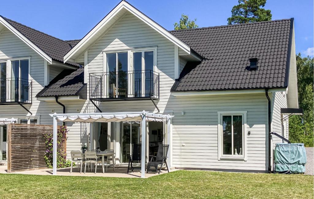 a white house with a porch with a table and chairs at Nice Home In Västervik With Lake View in Västervik