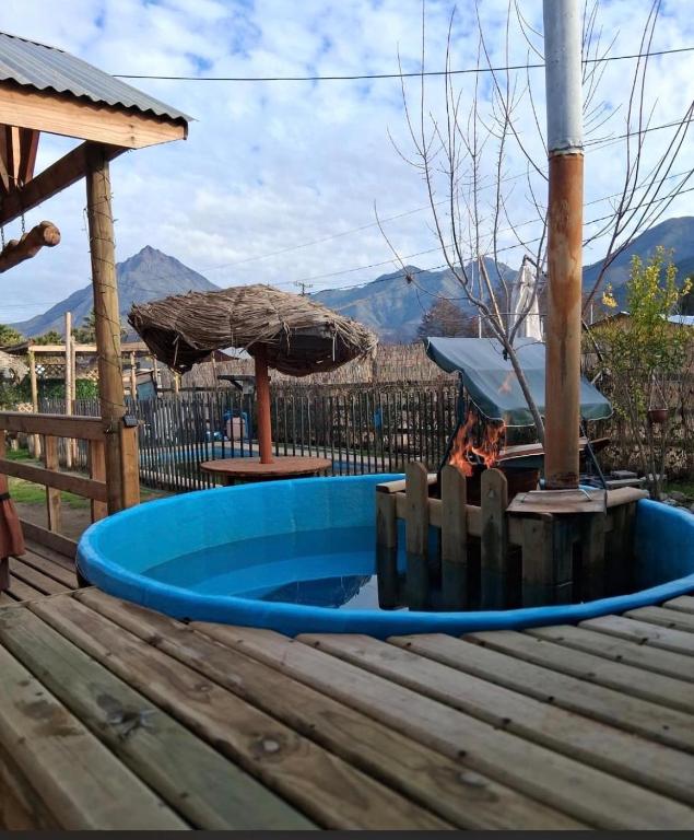 a blue pool on a wooden deck with a fire pit at Cabaña La campana in Hijuelas