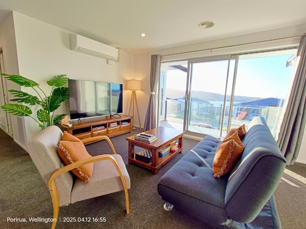 a living room with a couch and chairs and a tv at Waterview Spacious Bliss - 2 Beds in Porirua