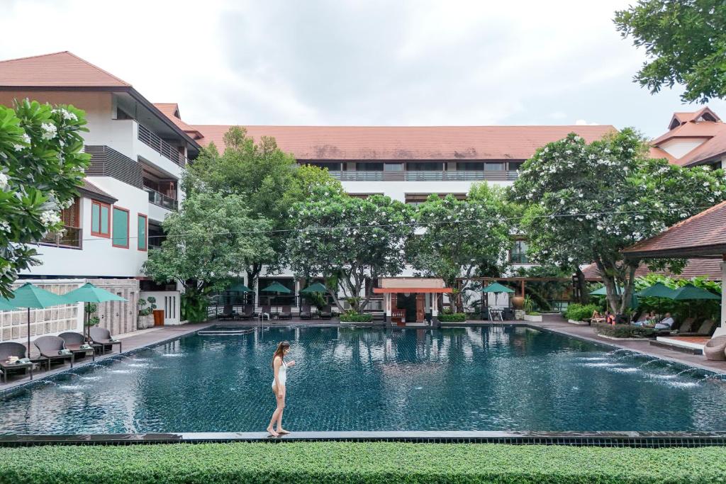 A large courtyard pool framed by resort buildings, trees, and shaded seating.