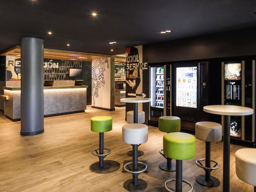 a room with stools and tables and a bedroom at Ibis Budget Málaga Aeropuerto Avenida de Velazquez in Málaga