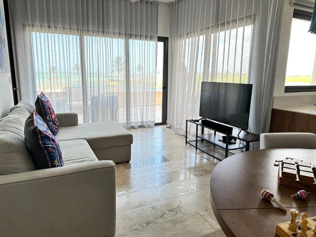 a living room with a couch and a tv and a table at Navela oceanfront apartment in Telchac Puerto