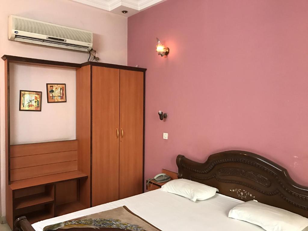 1 dormitorio con cama y pared de color rosa en Hotel D R International, en Ambāla
