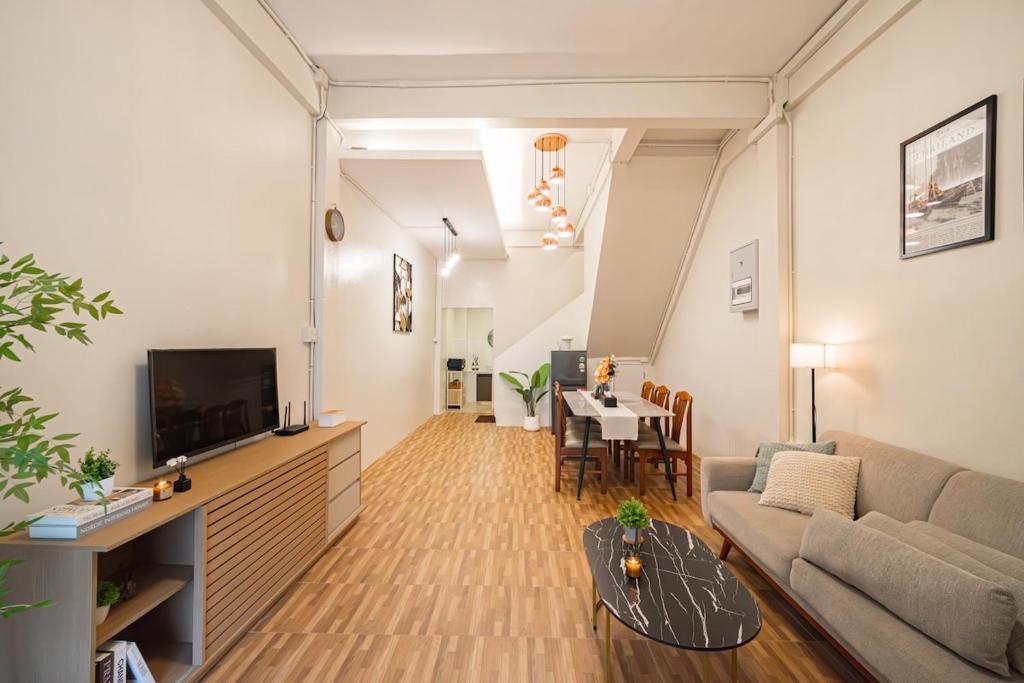 a living room with a couch and a tv and a table at Siam Place - Spacious Family House in Bangkok in Bangkok