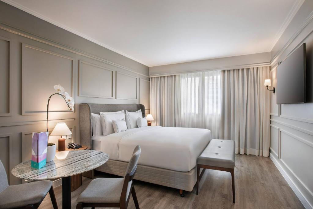 a hotel room with a large bed and a table at Meliá Campinas in Campinas