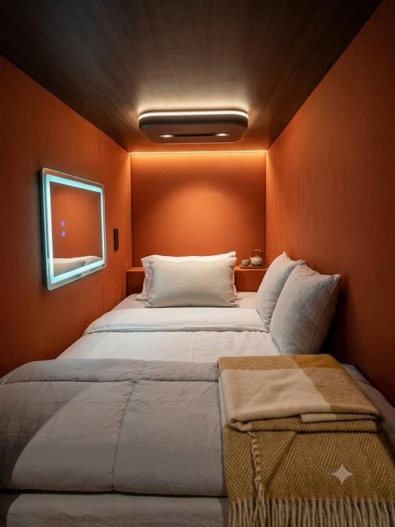 a large bed in a room with an orange wall at Capsule CDMX in Mexico City