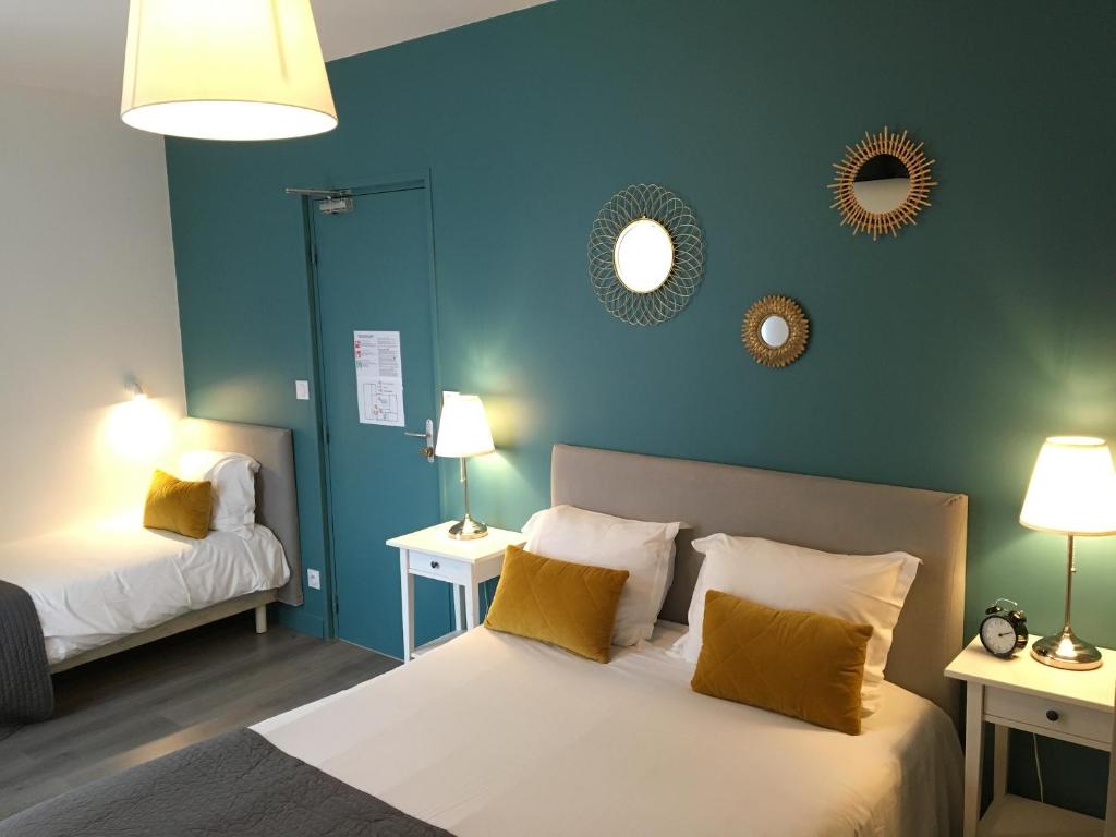 a bedroom with two beds with blue walls and mirrors at Hotel Saint-Michel in Dinard