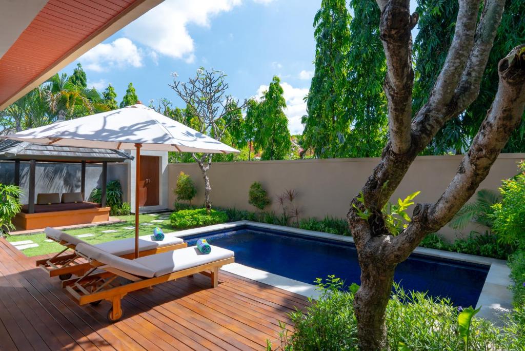 a patio with an umbrella and a swimming pool at The Yubi Boutique Villas Seminyak in Seminyak