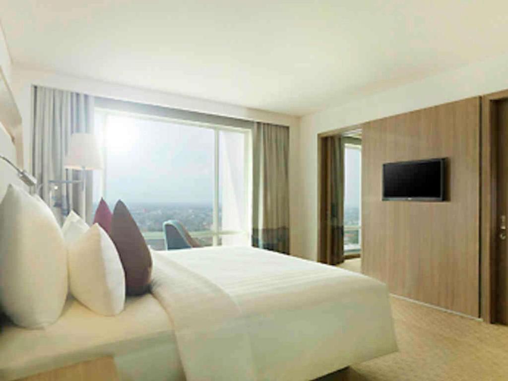 a hotel room with a bed with a large window at Novotel Tangerang in Tangerang