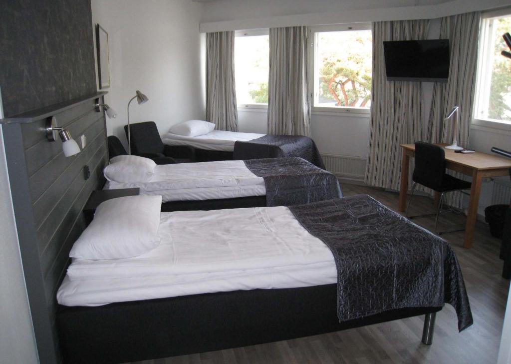 Habitación de hotel con 2 camas y escritorio en Hotelli Marilyn en Harjavalta