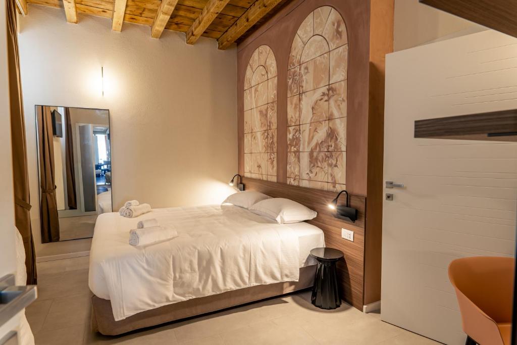 a bedroom with a white bed with a painting on the wall at Montenero City Rooms in Verona