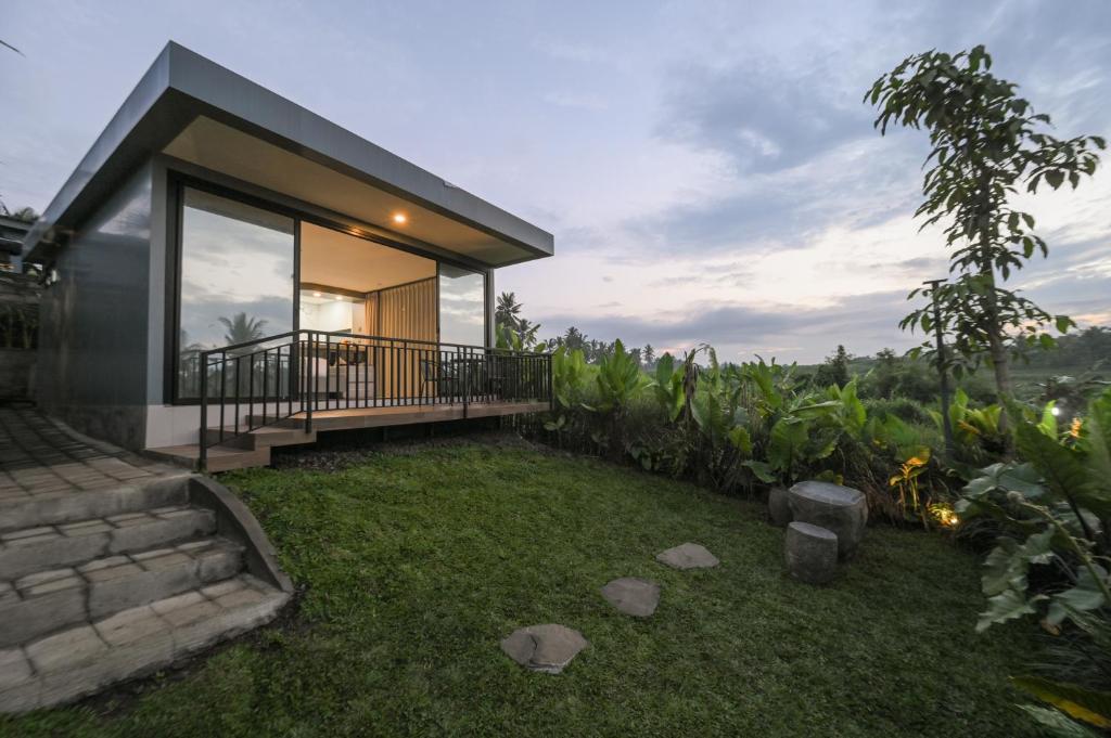 a small house with a balcony and a yard at Root and Rise Cabins in Tabanan