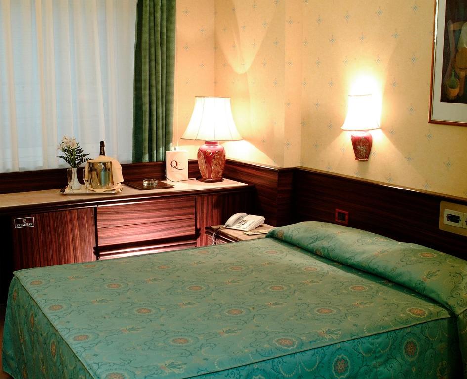a bedroom with a bed and a desk with a phone at Hotel Leonardo Da Vinci in Sassari