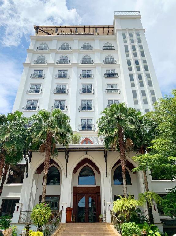a white building with palm trees in front of it at The Vientiane Capitol "Capitol Residence" in Vientiane