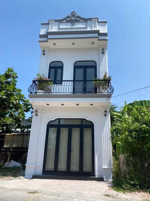 a white building with a balcony on top of it at Sunrak House in Ðạo Thành