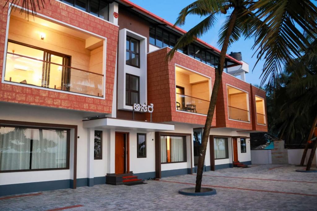 a building with a palm tree in front of it at Sunlit Shores Beach Villa in Kundapur