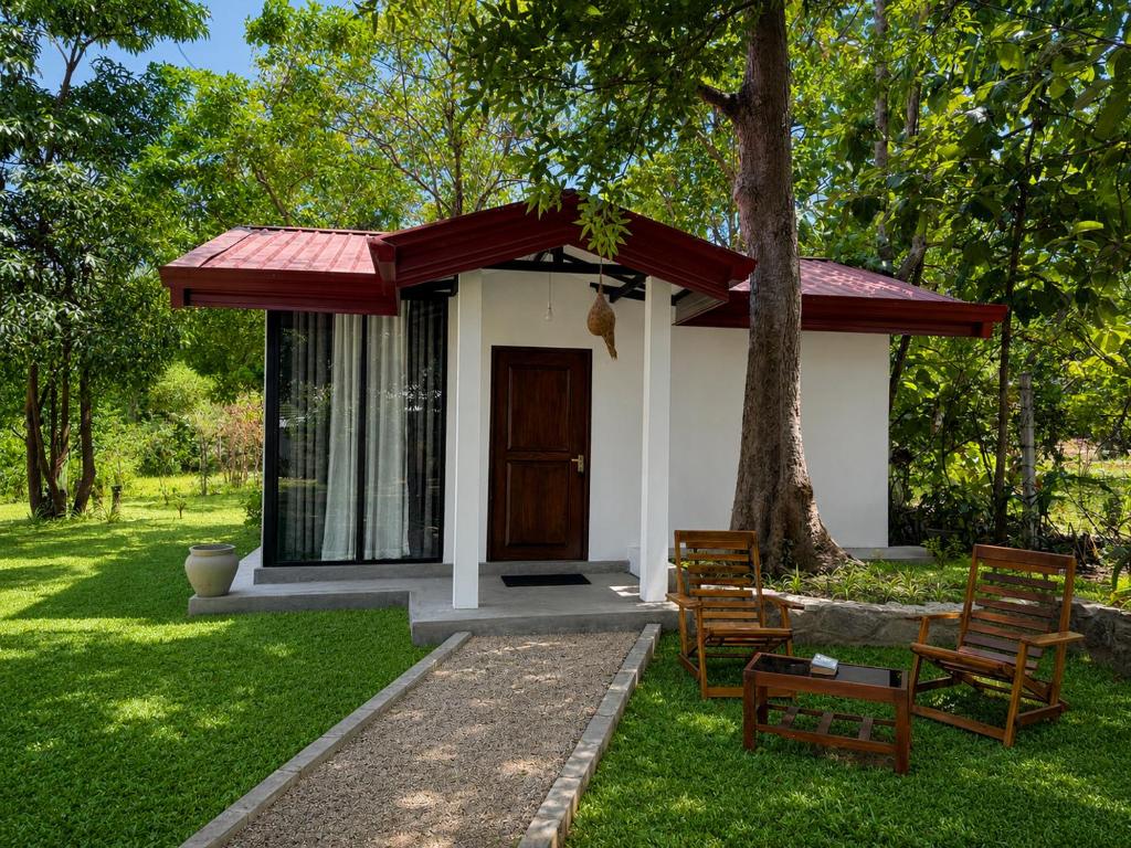 a small house with a red awning in a yard at Wihara Cottage Sigiriya in Sigiriya