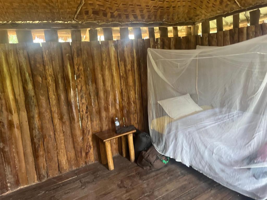 a bed in a room with a wooden fence at At the river campsite in Kihihi