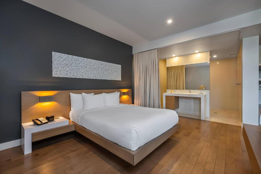 ein Schlafzimmer mit einem weißen Bett und einem Spiegel in der Unterkunft Hôtel du Lac Champlain, an Ascend Collection Hotel in Venise-en-Québec