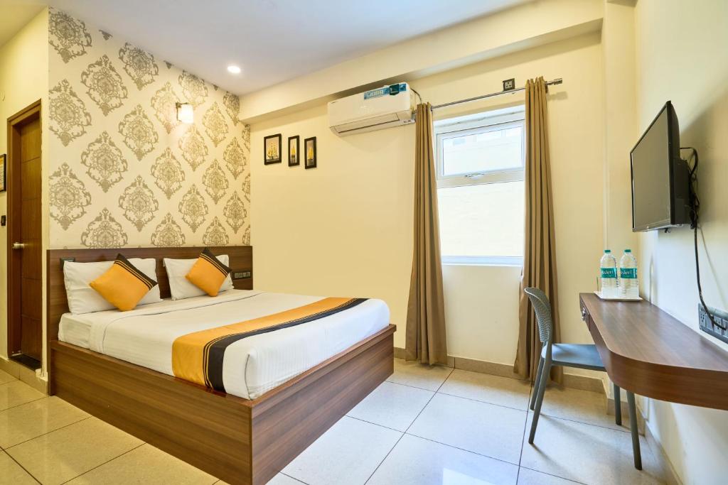 a bedroom with a bed and a desk and a television at Itsy Hotels NRM Residency - Near Mysore Palace in Mysore