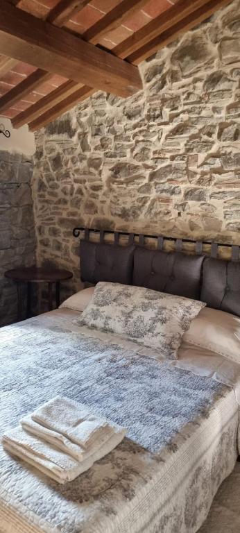 a bed in a room with a stone wall at Tuscany House Retreat in Casentino in Subbiano