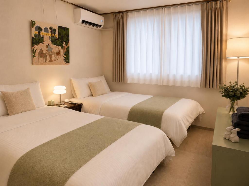 a hotel room with two beds and a window at Maison de Jann in Seoul