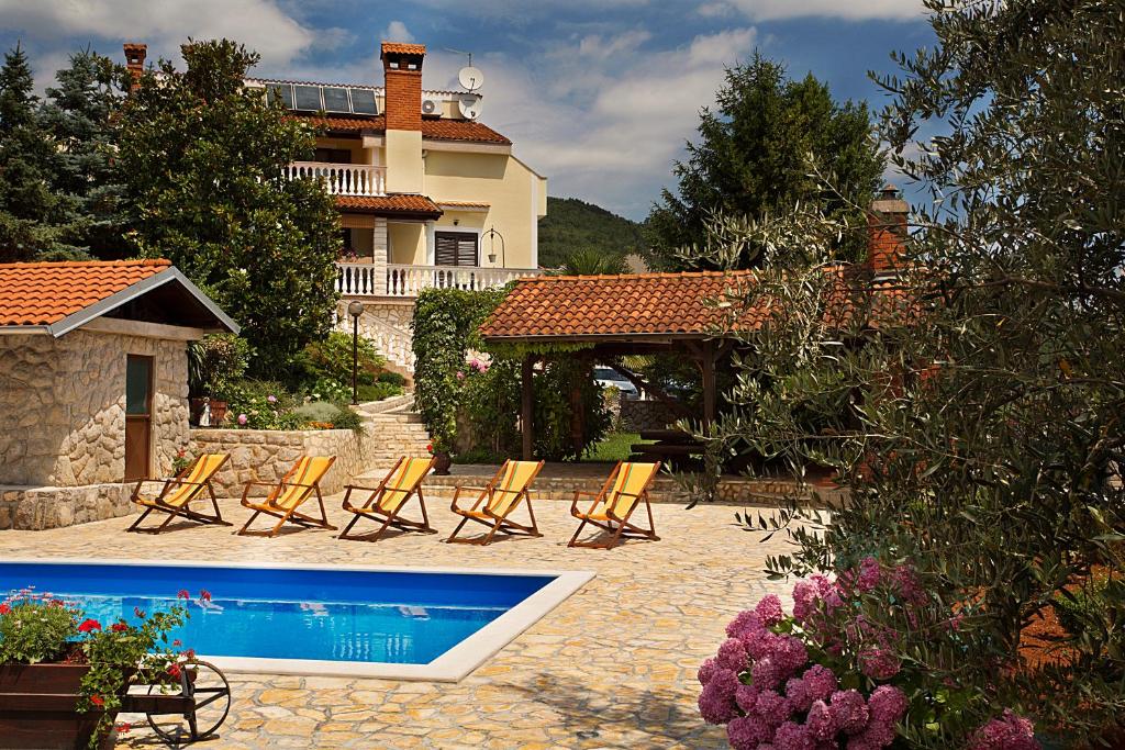 a group of chairs and a swimming pool in front of a house at Apartments Petricic with swimming pool in Ičići