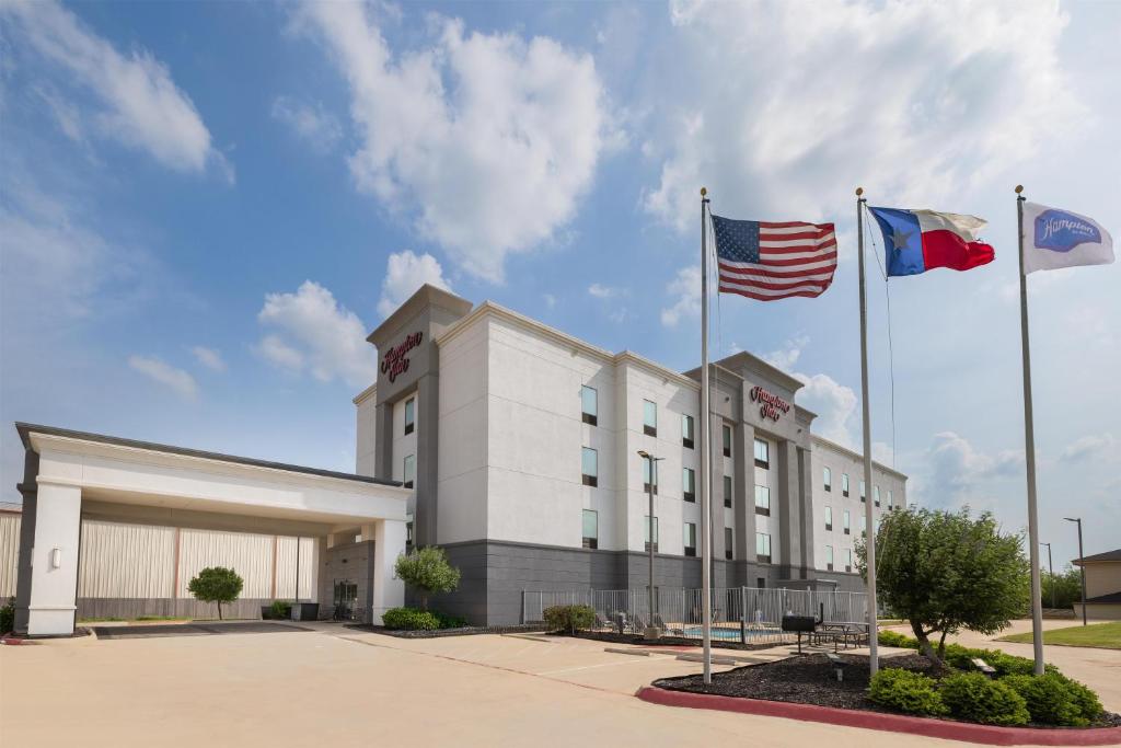 zwei Flaggen wehen vor einem Gebäude in der Unterkunft Hampton Inn Cotulla in Cotulla