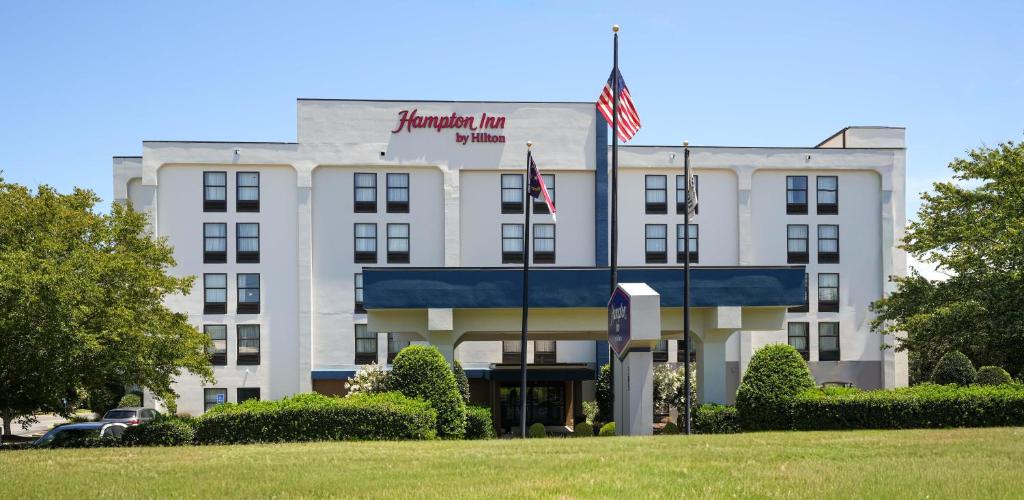 a white building with an american flag in front of it at Hampton Inn Henderson in Henderson