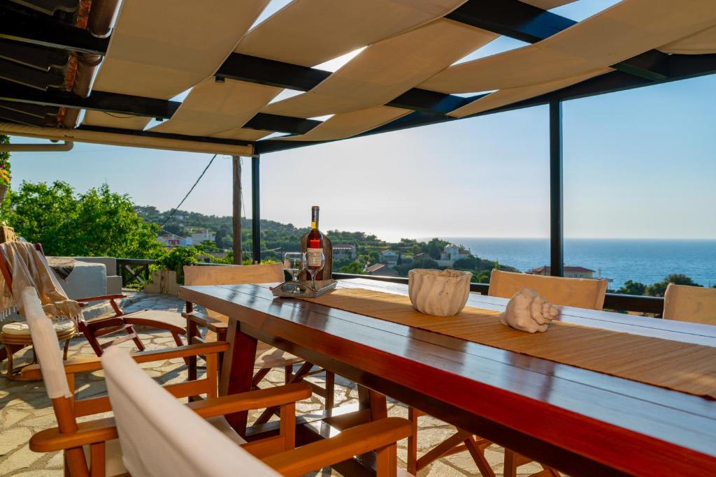 a wooden table with chairs and a bottle of wine at Agnanti Seaview Villas in Karlovasi