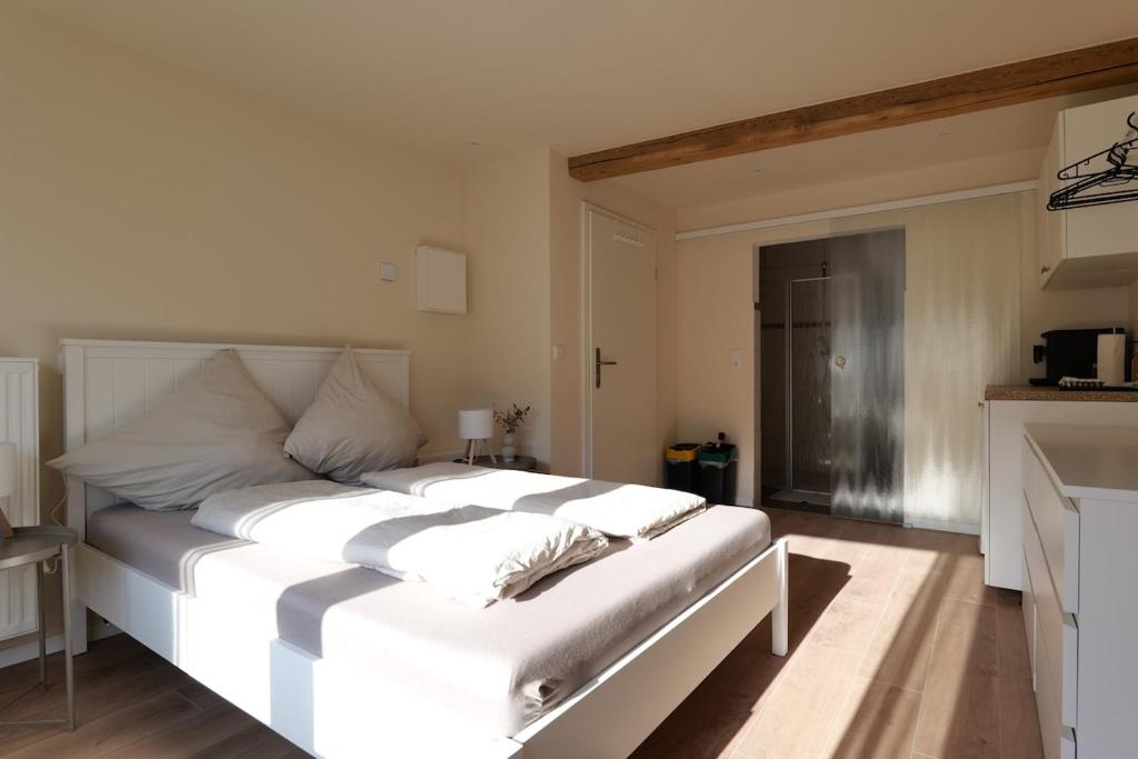 a large white bed in a room with a kitchen at MoselStudio Briedel - Sonnenterrasse und Komfort in Briedel