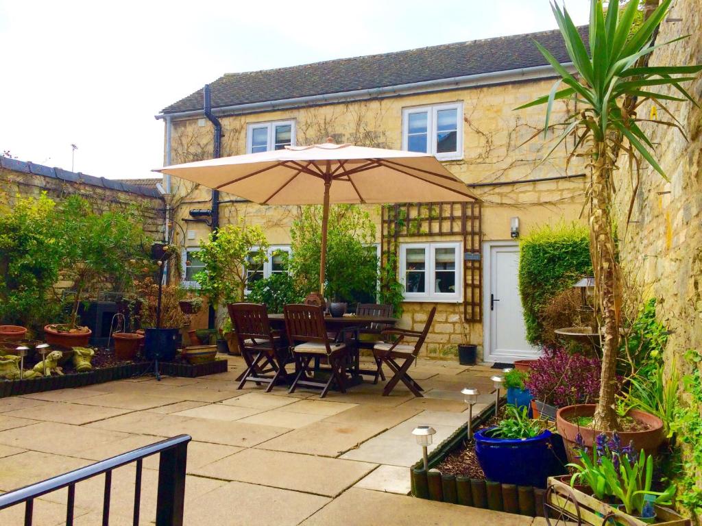 a patio with an umbrella and a table and chairs at Troy House in Painswick