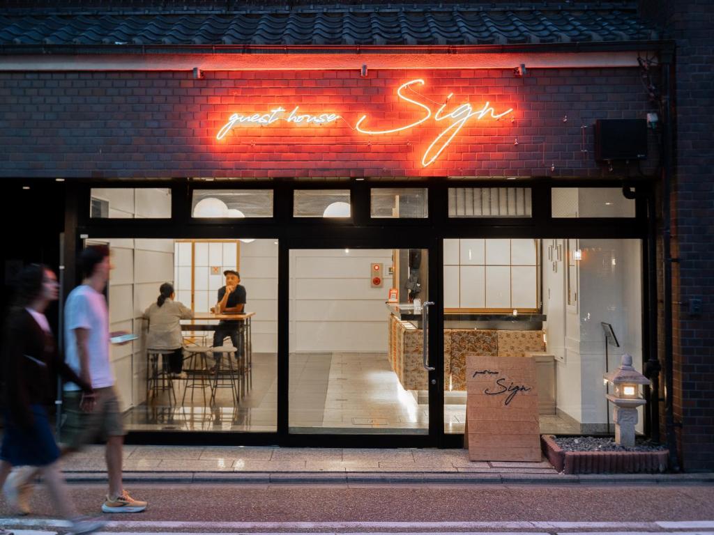 a store front with a neon sign in the window at Guesthouse Sign in Kyoto