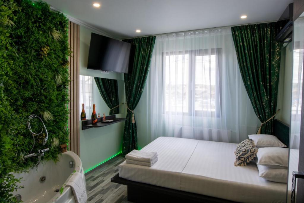 a bedroom with a bed and a tub and a window at Elma Nest in Drobeta-Turnu Severin