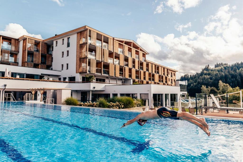 a man swimming in a swimming pool at a hotel at Das Hohe Salve Sportresort, 4 Sterne Superior in Hopfgarten im Brixental