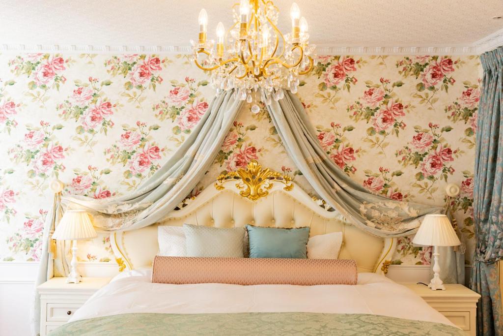 a bedroom with a canopy bed with floral wallpaper at WhiteRunse in Takayama