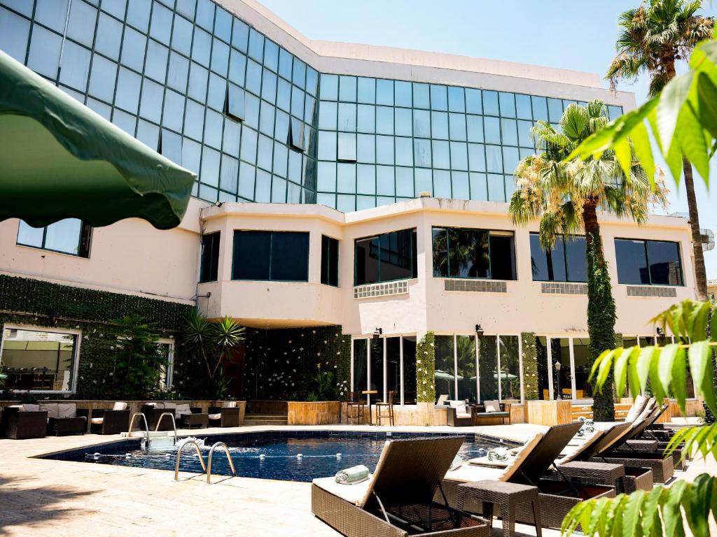 a hotel with a swimming pool and lounge chairs in front of a building at Amman West Hotel , A Boutique Hotel in Amman
