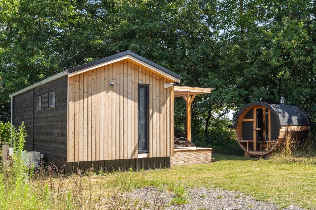 a small wooden shed and a wooden barrel in a field at The Wellness View! in Hoogersmilde