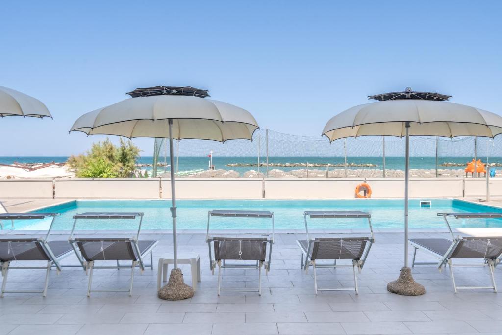 a group of tables and umbrellas next to a swimming pool at Hotel Embassy in Pesaro