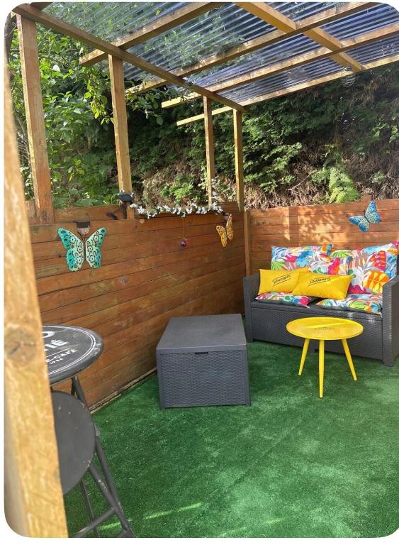 a patio with a couch and a table and butterflies at Caravane revisité in Pleslin-Trigavou