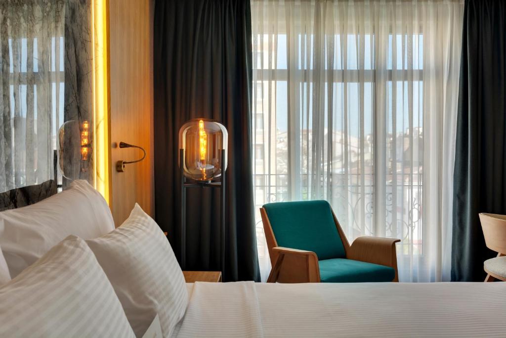 a bedroom with a bed and a chair and a window at Grande Arte Hotel in Eskisehir