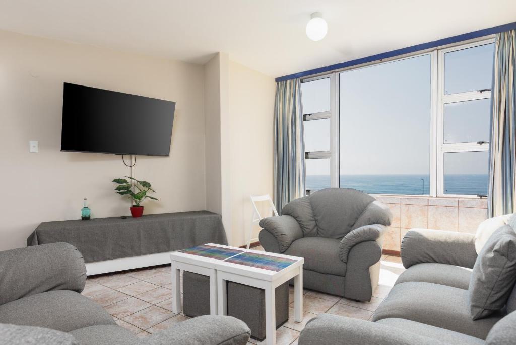 a living room with two chairs and a flat screen tv at Peacehaven 108 in Scottburgh