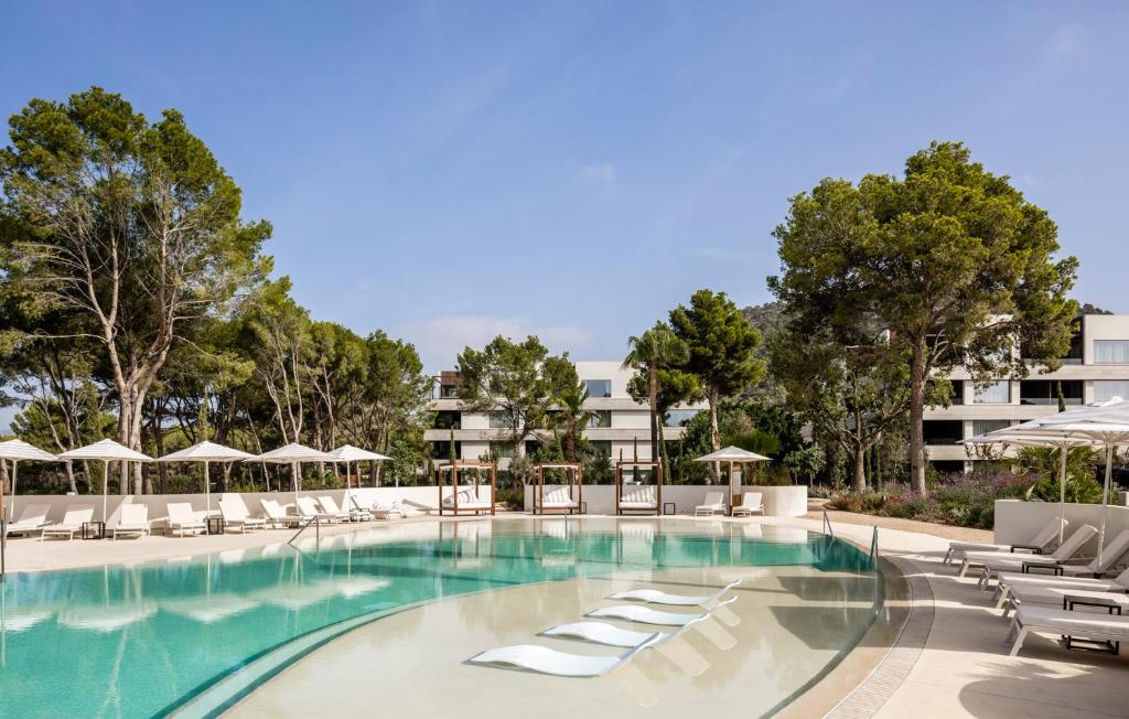 a swimming pool with lounge chairs and umbrellas at Kimpton Aysla Mallorca by IHG in Santa Ponsa