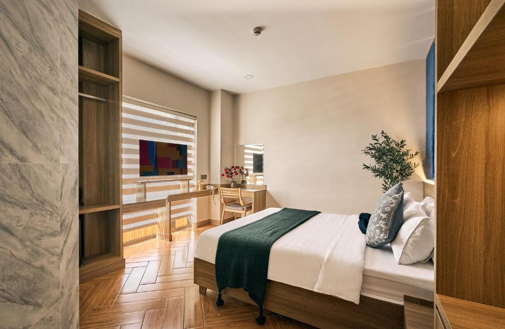 a bedroom with a bed and a desk and a window at Tran Long Hotel By Urban B in Ho Chi Minh City