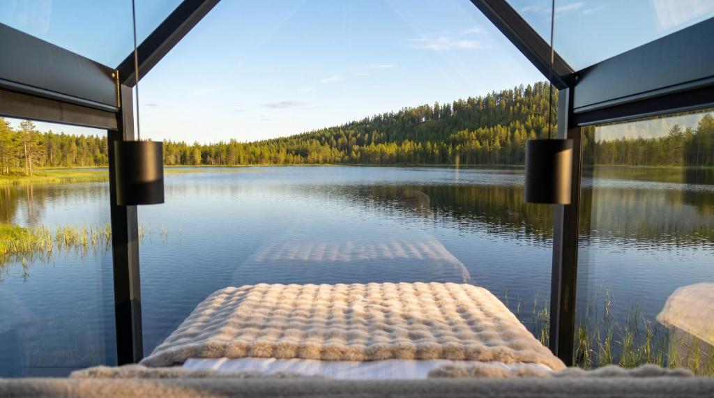 a view of a lake from the inside of a house at Sāmeland Retreat, Mirrored Glass Cabins, Swedish Lapland in Arvidsjaur