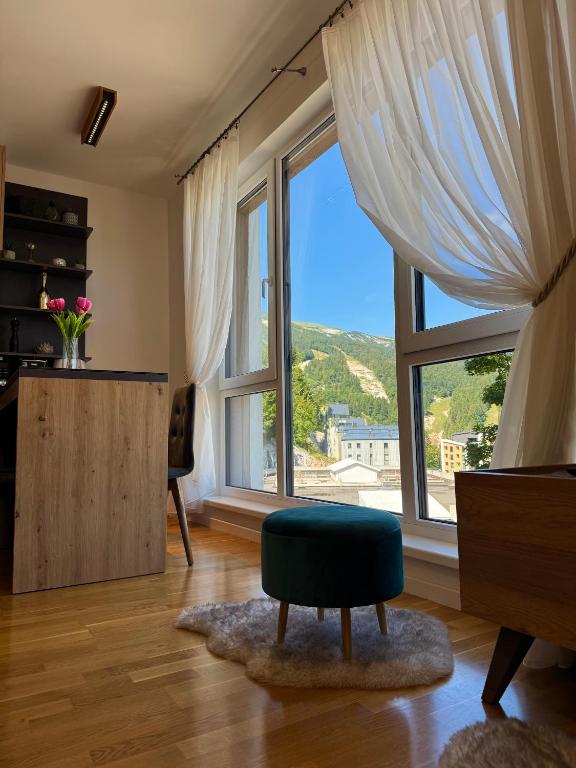 a living room with a large window and a green chair at Bjelašnica Slope View in Bjelašnica