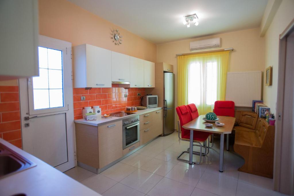 a kitchen with a small table and red chairs at Sofia's Delightful Apartment in Argostoli