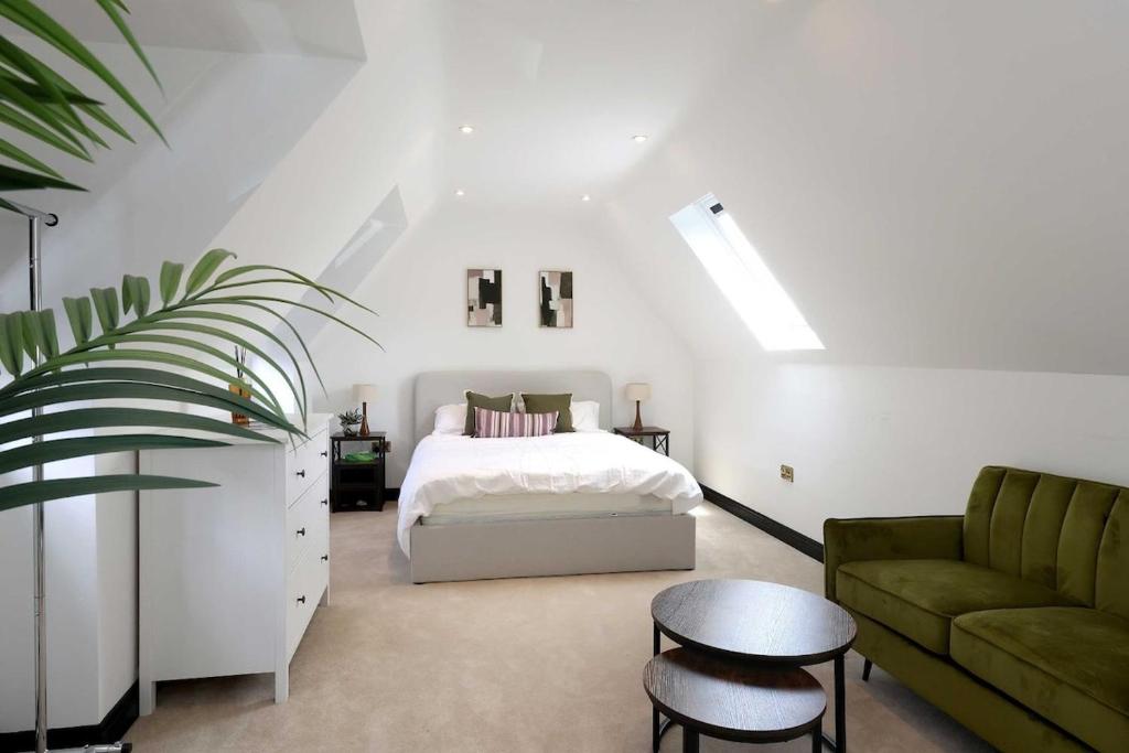 a bedroom with a bed and a green couch at Wings Annexe in Beaconsfield
